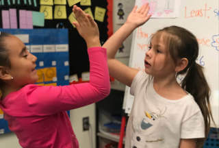 Kids do a high five in classroom