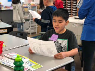 Boy in classroom reading a sheet